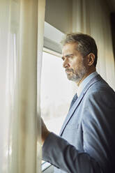 Portrait of businessman looking out of window - ZEDF03127