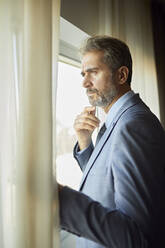 Portrait of businessman looking out of window - ZEDF03128