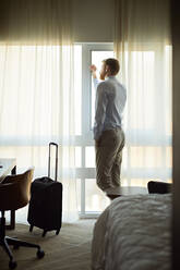 Geschäftsmann im Hotelzimmer schaut aus dem Fenster - ZEDF03131