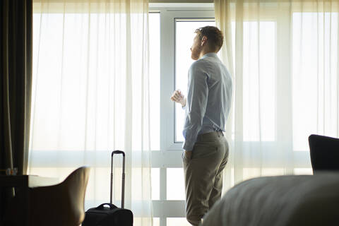 Geschäftsmann im Hotelzimmer schaut aus dem Fenster, lizenzfreies Stockfoto
