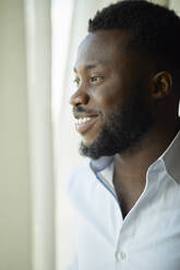 Portrait of smiling businessman looking out of window - ZEDF03139