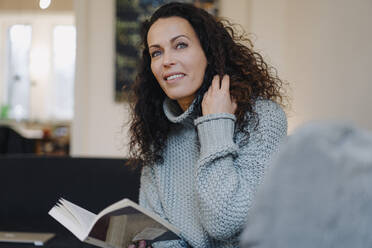 Woman sitting on couch, reading book, thinking - JOSEF00005