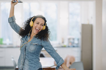 Happy smiling woman listening music and dancing in pajamas at