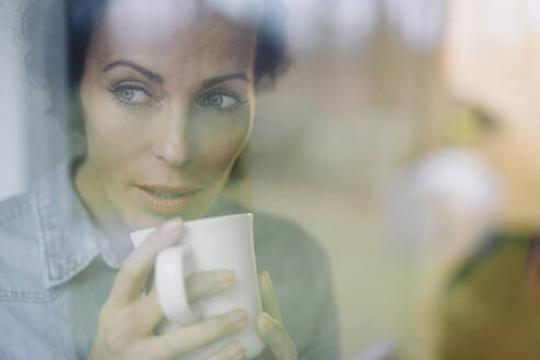 Woman drinking coffee, looking out of window - JOSEF00025