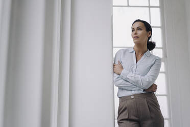 Erfolgreiche Geschäftsfrau, am Fenster stehend, an die Wand gelehnt, nachdenklich - JOSEF00036