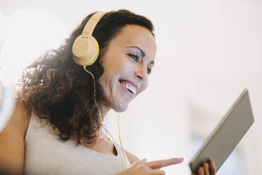 Frau mit Kopfhörer, mit digitalem Tablet, lächelnd - JOSEF00043
