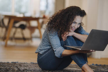 Woman sitting on floor, using laptop, smiling - JOSEF00072