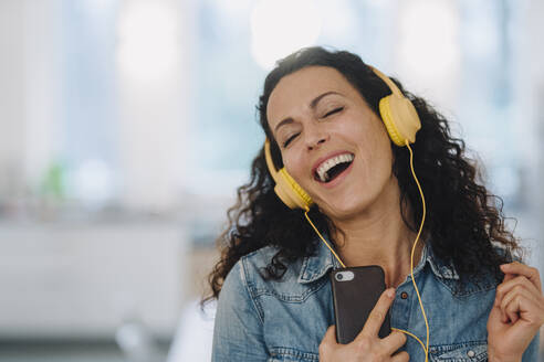 Glückliche Frau, die Musik hört, singt und tanzt, mit Smartphone und Kopfhörern - JOSEF00084