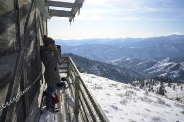 Female Taking Photograph From A Fire Lookout In The Mountains - CAVF75561