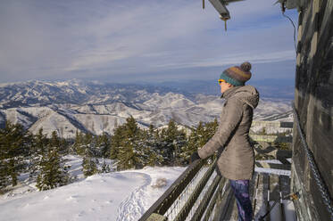 Female Looking Into The Distance From A Fire Lookout In The Mountains - CAVF75565