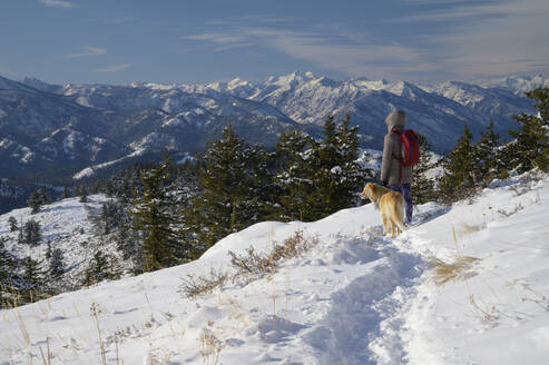 Wanderin und Hund blicken in die Ferne der Berge - CAVF75571