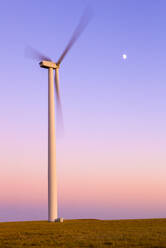 Windturbine in Bewegung gegen lila Himmel mit Mond - CAVF75624