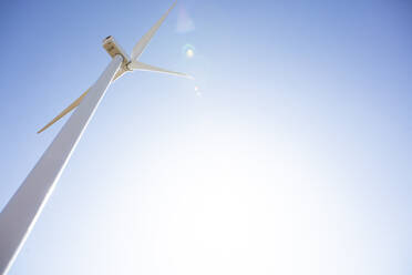 Windturbine gegen blauen Himmel mit Sonnenerscheinung - CAVF75649