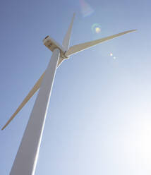 Windturbine gegen blauen Himmel mit Sonnenerscheinung - CAVF75650