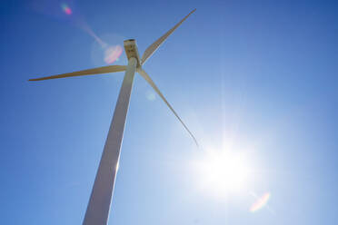 Windturbine gegen blauen Himmel mit Sonnenerscheinung - CAVF75653