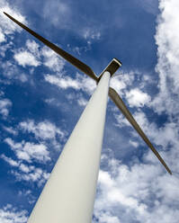 Windturbine aus niedrigem Winkel gegen bewölkten blauen Himmel - CAVF75667