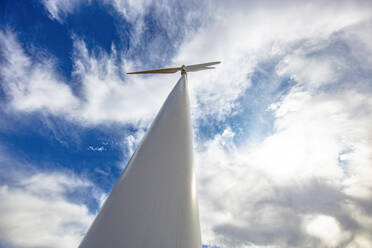 Wind Turbine low angle against cloudy blue sky - CAVF75670