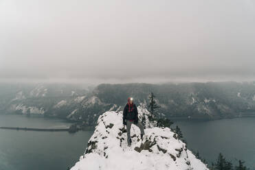 Eine junge Frau steht auf dem Gipfel eines verschneiten Berges in der Columbia-Schlucht - CAVF75673