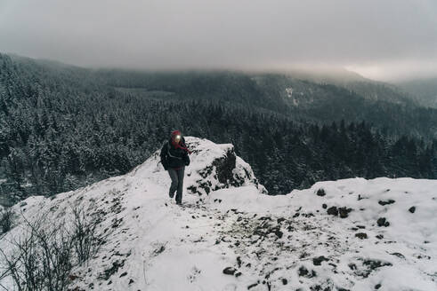 Eine junge Frau wandert zum Gipfel eines verschneiten Punktes in der Columbia Gorge - CAVF75674