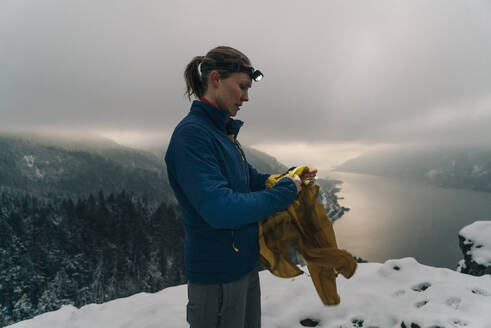 Eine junge Frau steht auf dem Gipfel eines verschneiten Berges in der Columbia-Schlucht - CAVF75679