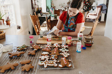 Mädchen dekorieren Weihnachtsplätzchen mit Zuckerguss und Streuseln - CAVF75832