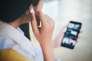 Eine junge Frau hört Online-Musik auf ihrem Mobiltelefon. - CAVF75836