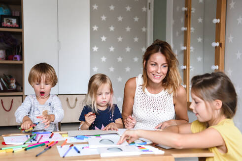 Mutter mit kleinen Kindern, die mit Filzstiften zeichnen - CAVF75857