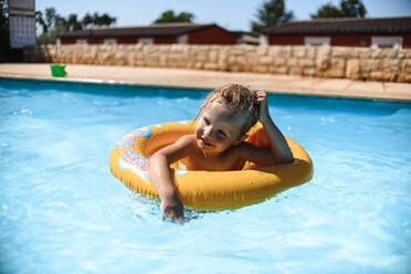 Kleines Mädchen schwimmt im Pool Im Gummiring - CAVF75876