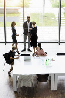 Geschäftsleute schütteln sich die Hände in einem modernen Bürokonferenzraum - BMOF00286