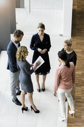 Business people standing in modern office building discussing project - BMOF00290