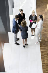 Business people standing in modern office building discussing project - BMOF00291