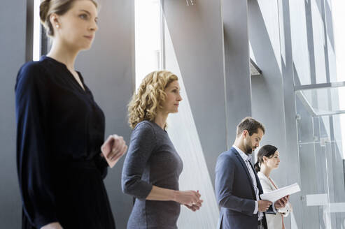 Businesswomen and businessmen waiting in line in the office - BMOF00300