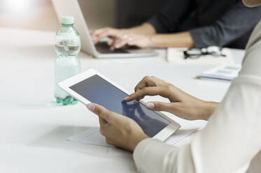 Close-up of businesswoman using tablet during a meeting in office - BMOF00306