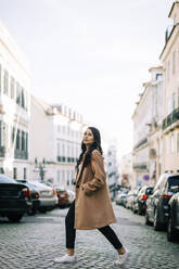 Porträt einer modischen jungen Frau beim Überqueren der Straße, Lissabon, Portugal - DCRF00009