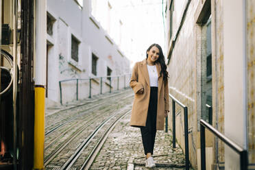 Porträt einer modischen jungen Frau, die die Straße entlanggeht, Lissabon, Portugal - DCRF00010