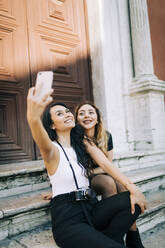 Portrait of two young women taking selfie with smartphone, Lisbon, Portugal - DCRF00016