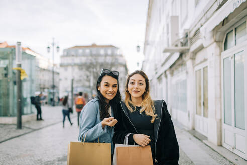 Porträt von zwei jungen Frauen mit Einkaufstüten in der Stadt, Lissabon, Portugal - DCRF00022