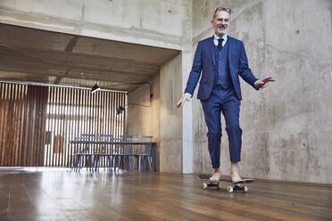 Senior Geschäftsmann skateboarding in seinem Büro - MCF00613