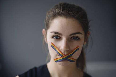 Portrait of young woman with LGBT sticky tape on her mouth - KNSF07636