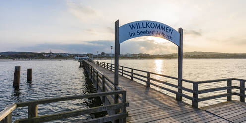 Germany, Mecklenburg-Western Pomerania, Heringsdorf, Welcome sign over empty wooden pier at sunset - WDF05845