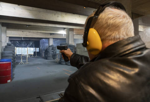 Älterer Mann zielt mit einer Pistole auf dem Schießstand - AHSF01967