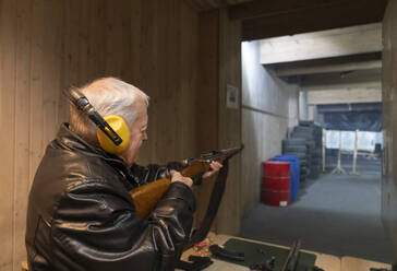 Älterer Mann zielt mit einem Gewehr auf dem Schießstand - AHSF01968