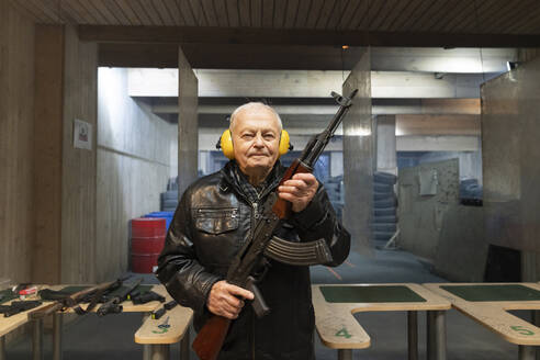 Porträt eines älteren Mannes mit einem Gewehr im Schießstand - AHSF01970