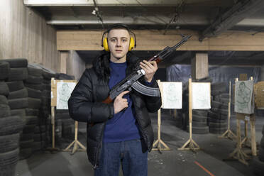 Porträt eines jungen Mannes mit einem Gewehr im Schießstand - AHSF01975