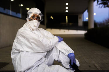 Female scientist wearing protective suit and mask in front of a laboratory - ERRF02750