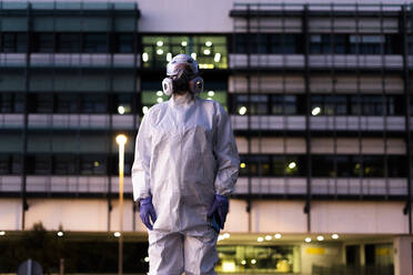 Female scientist wearing protective suit and mask in front of a laboratory - ERRF02752
