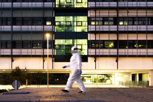 Female scientist wearing protective suit and mask in front of a laboratory - ERRF02755