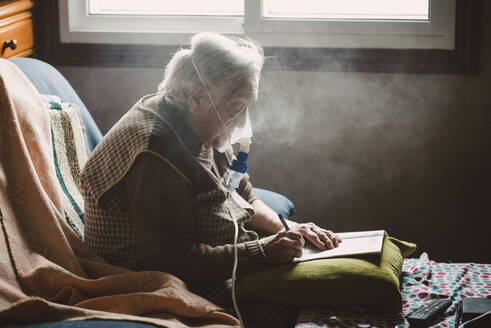 Ältere Frau benutzt Inhalationsgerät zu Hause - RAEF02360