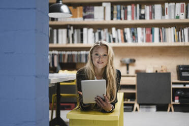 Junge Geschäftsfrau auf einer Bank in einem Loft-Büro liegend mit einem Tablet - GUSF03366