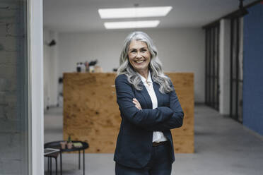 Porträt einer lächelnden grauhaarigen Geschäftsfrau in einem Loftbüro - GUSF03398